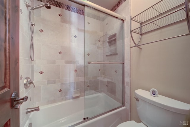 bathroom featuring toilet and shower / bath combination with glass door