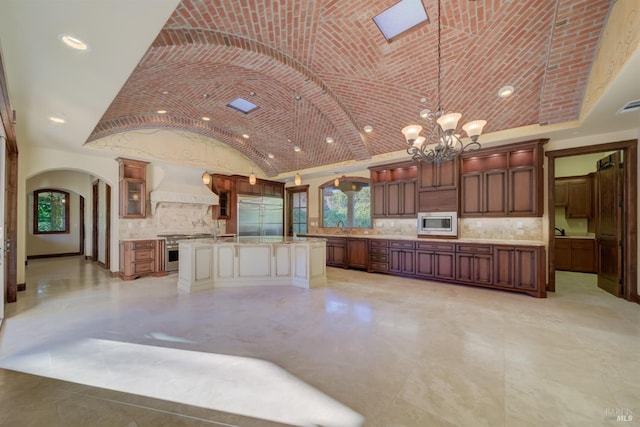 kitchen featuring a center island, premium range hood, an inviting chandelier, hanging light fixtures, and built in appliances