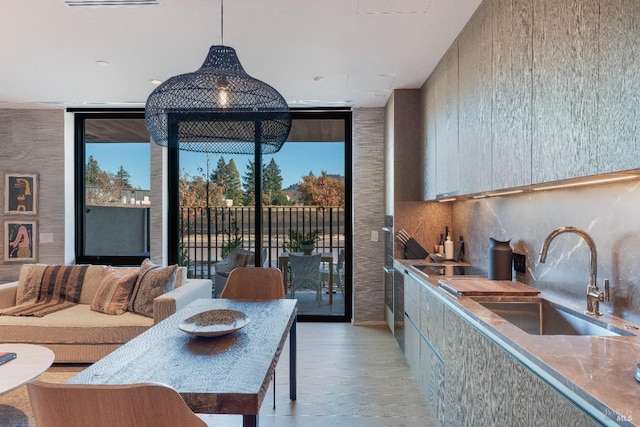 dining room featuring a wall of windows, sink, and light wood-type flooring