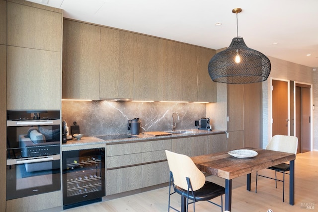 kitchen with beverage cooler, decorative light fixtures, decorative backsplash, black electric stovetop, and light wood-type flooring