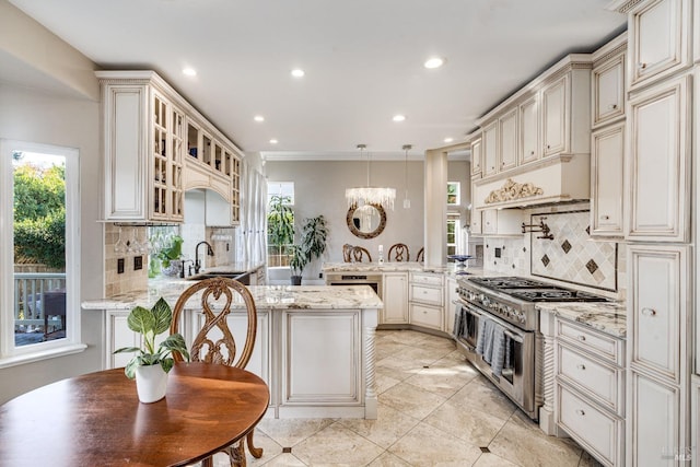 kitchen featuring light stone countertops, backsplash, sink, decorative light fixtures, and double oven range