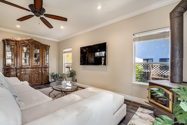 living room featuring ceiling fan, crown molding, a wood stove, and dark wood-type flooring