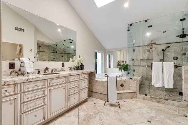 bathroom with plus walk in shower, vanity, and lofted ceiling with skylight