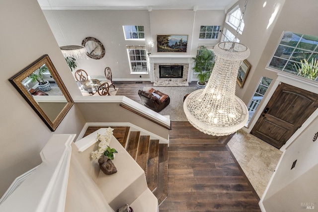 interior space with hardwood / wood-style floors, a towering ceiling, a fireplace, and ornamental molding