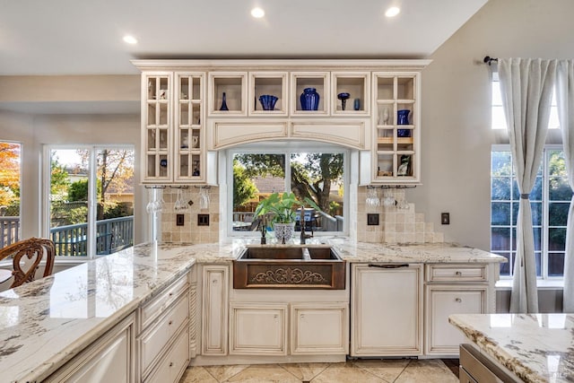 kitchen with light stone countertops, backsplash, and sink