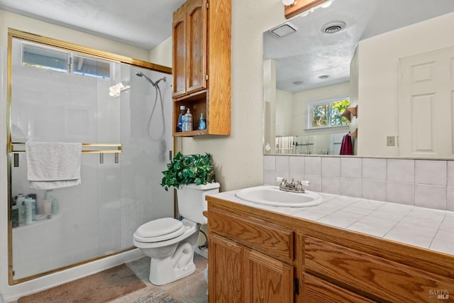 bathroom with decorative backsplash, a textured ceiling, vanity, a shower with door, and toilet