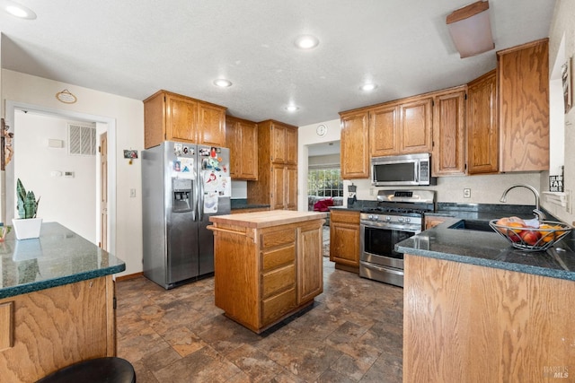 kitchen featuring a center island, dark stone countertops, sink, and appliances with stainless steel finishes