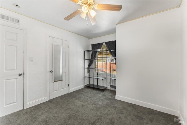 empty room with ceiling fan and dark colored carpet