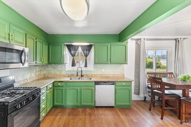 kitchen with appliances with stainless steel finishes, light hardwood / wood-style flooring, green cabinetry, and sink