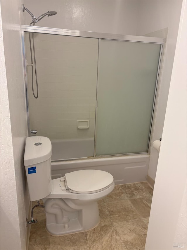 bathroom with toilet and bath / shower combo with glass door