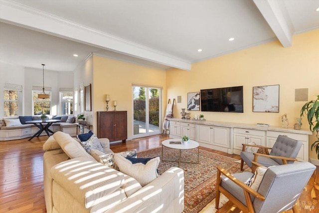 living room featuring ornamental molding, light hardwood / wood-style floors, and beamed ceiling