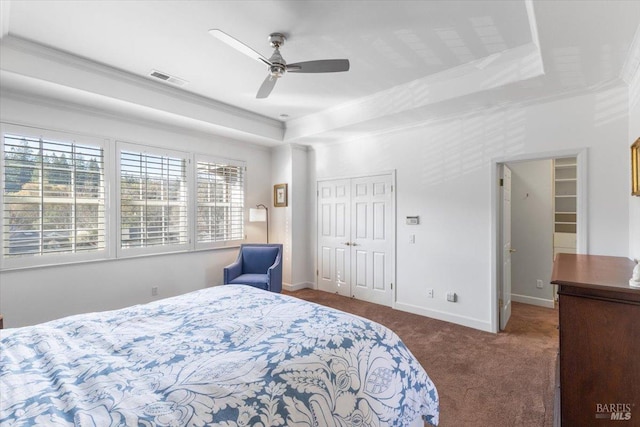 carpeted bedroom featuring ornamental molding, a closet, ceiling fan, and a tray ceiling