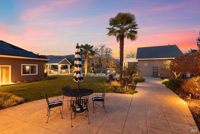 patio terrace at dusk featuring a lawn