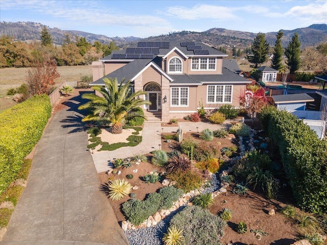 view of front property with a mountain view and solar panels