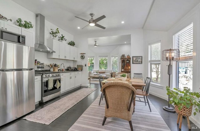 kitchen with wall chimney exhaust hood, white cabinetry, plenty of natural light, and appliances with stainless steel finishes