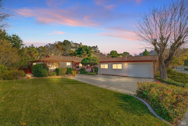 ranch-style house featuring a garage and a lawn