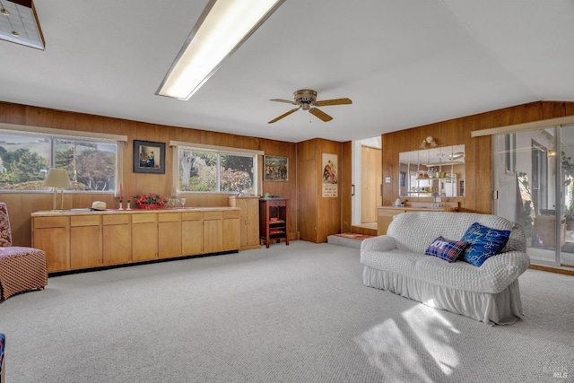 living room featuring wood walls, plenty of natural light, light carpet, and lofted ceiling