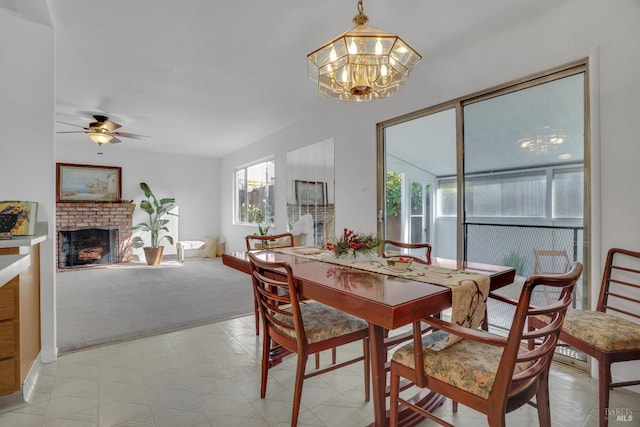 dining area with ceiling fan with notable chandelier, light colored carpet, and a fireplace