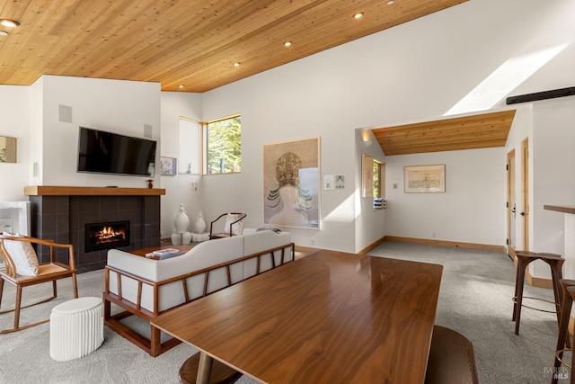 carpeted dining space with wooden ceiling, high vaulted ceiling, and a tiled fireplace