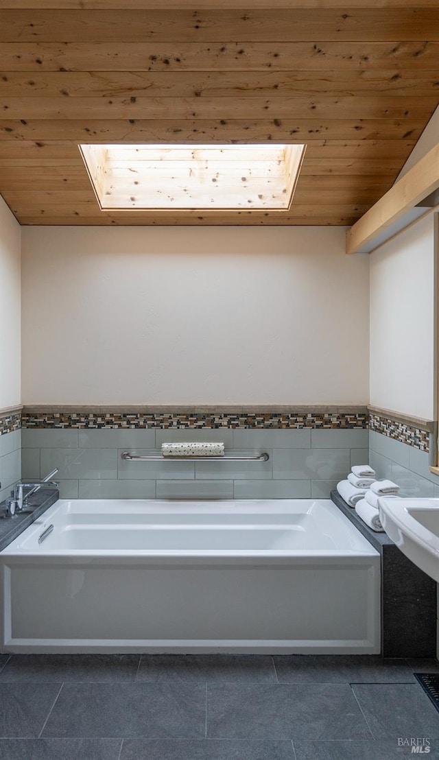 bathroom featuring tile patterned floors, wooden ceiling, a tub, and a skylight