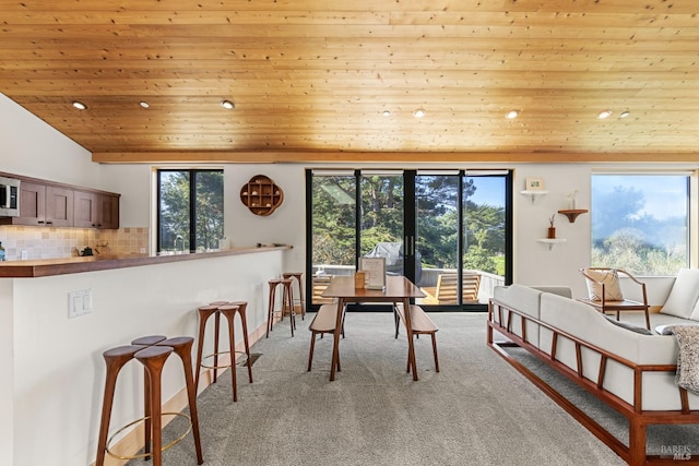 carpeted dining room featuring vaulted ceiling and wood ceiling