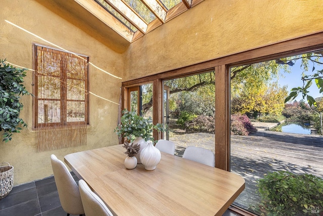 dining area featuring lofted ceiling with skylight and dark tile patterned floors