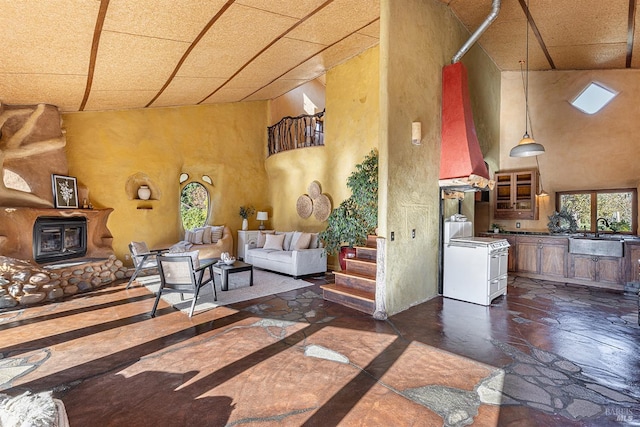 living room featuring a wood stove, sink, and a high ceiling