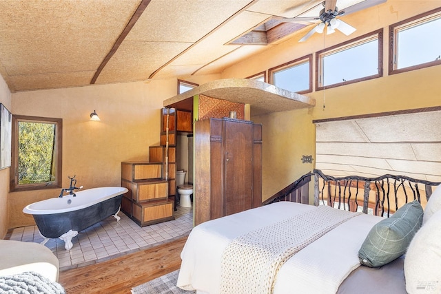 bedroom featuring wood-type flooring, ensuite bathroom, multiple windows, and ceiling fan