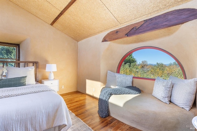 bedroom with hardwood / wood-style floors and lofted ceiling