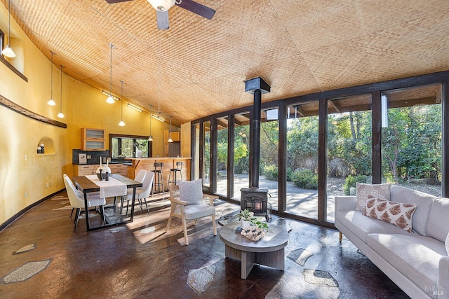 sunroom / solarium with lofted ceiling, ceiling fan, and a wood stove