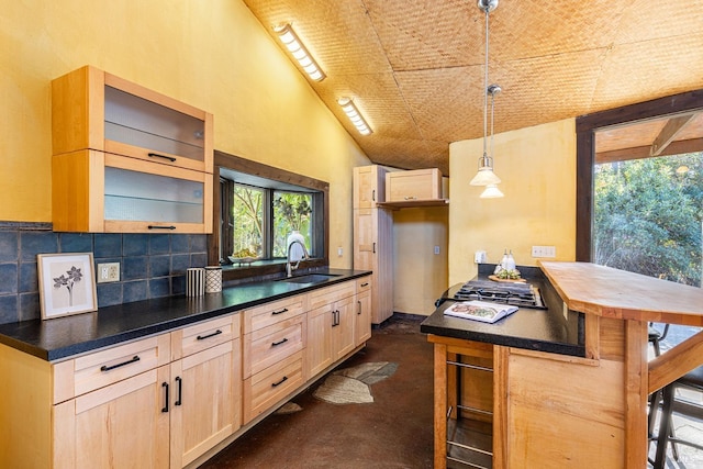 kitchen with a kitchen breakfast bar, light brown cabinetry, sink, and decorative light fixtures