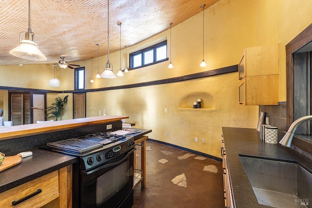 kitchen with pendant lighting, black stove, sink, and a high ceiling