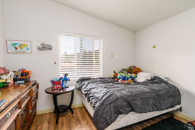 bedroom with wood-type flooring and vaulted ceiling