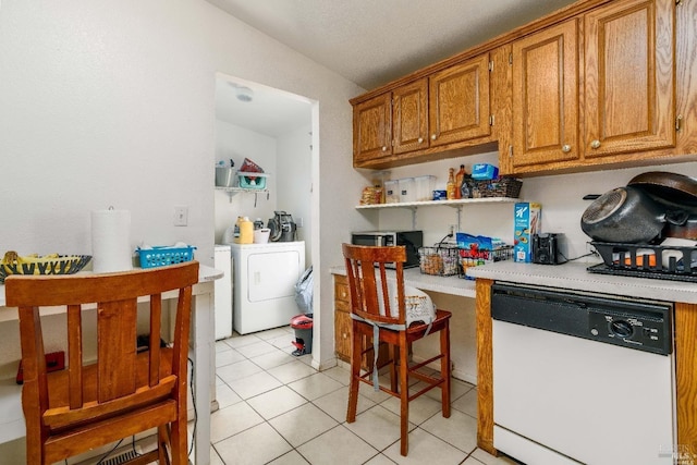 kitchen with white dishwasher, separate washer and dryer, light tile patterned floors, and vaulted ceiling