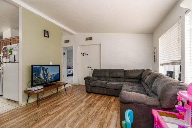 living room with vaulted ceiling with beams and light hardwood / wood-style floors