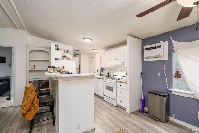 kitchen with a wall mounted air conditioner, light hardwood / wood-style flooring, white appliances, a breakfast bar, and white cabinets