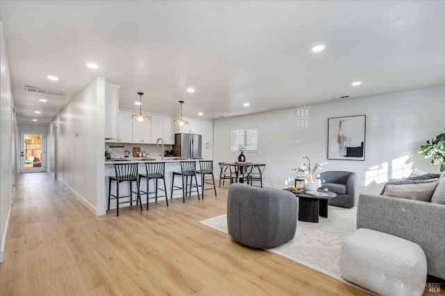 living room featuring light hardwood / wood-style flooring, a healthy amount of sunlight, and sink