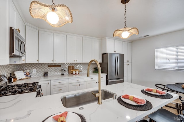 kitchen with decorative light fixtures, light stone counters, white cabinetry, and stainless steel appliances