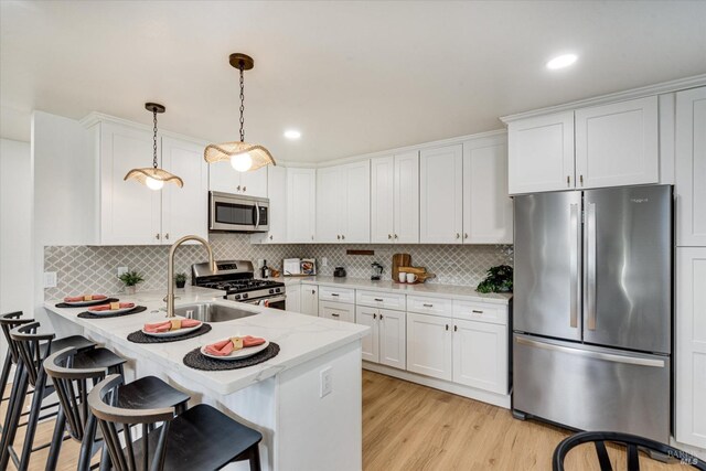 kitchen with white cabinetry, stainless steel appliances, kitchen peninsula, pendant lighting, and light hardwood / wood-style floors