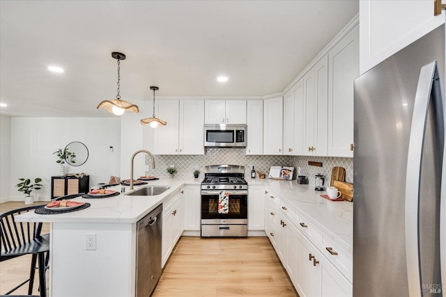 kitchen with pendant lighting, sink, light wood-type flooring, white cabinetry, and stainless steel appliances