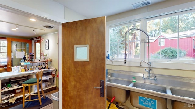 kitchen with a wealth of natural light, sink, stainless steel counters, and tile patterned flooring