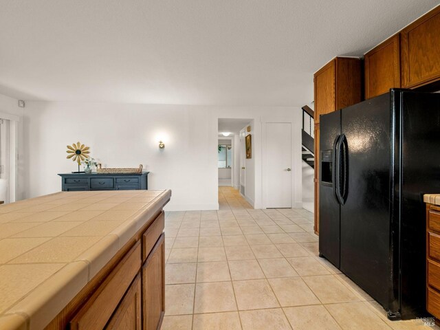 kitchen with tile counters, plenty of natural light, and black dishwasher