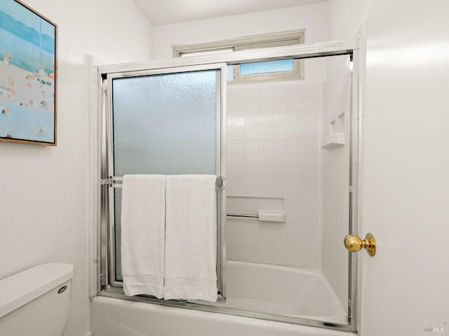 bathroom featuring toilet and combined bath / shower with glass door