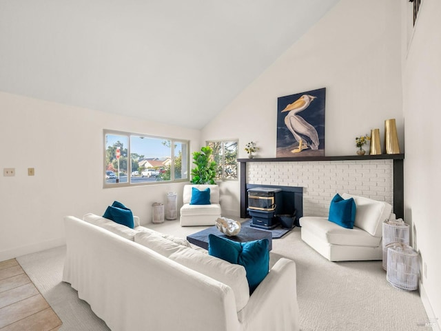 living room with a wood stove, high vaulted ceiling, and light colored carpet