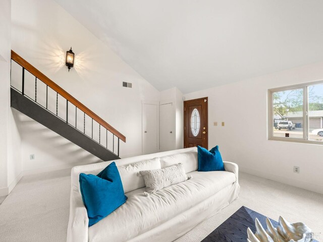 carpeted living room with high vaulted ceiling