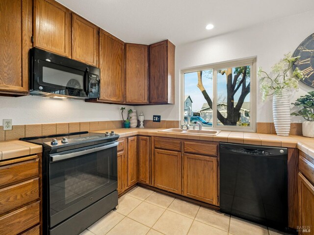 kitchen with a kitchen bar, kitchen peninsula, tile countertops, and black appliances