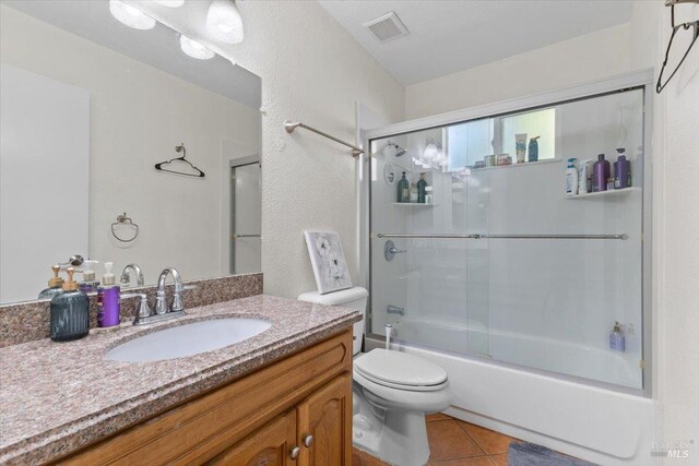 full bathroom featuring tile patterned floors, vanity, toilet, and enclosed tub / shower combo