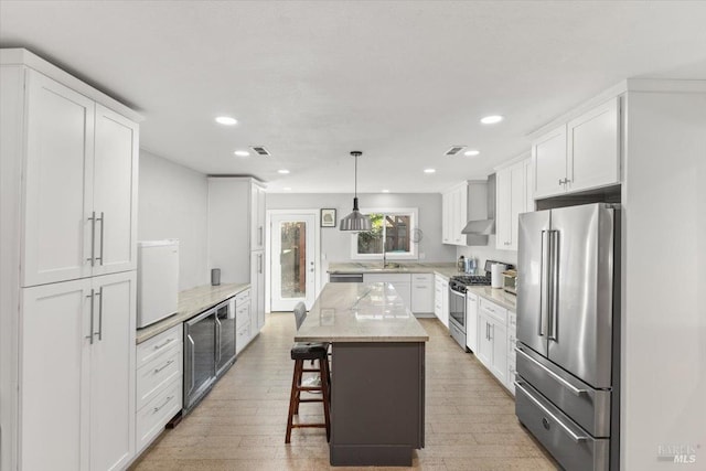 kitchen featuring pendant lighting, white cabinets, light hardwood / wood-style floors, appliances with stainless steel finishes, and a kitchen island