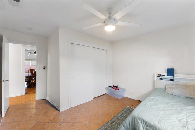 bedroom with ceiling fan, light tile patterned floors, and a closet