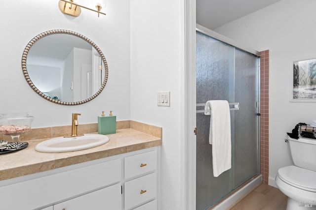 bathroom featuring toilet, a shower with shower door, and vanity